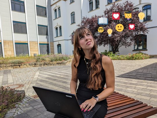 Frau lernt mit Laptop vorm Bildungszentrum ist von Emojis umgeben